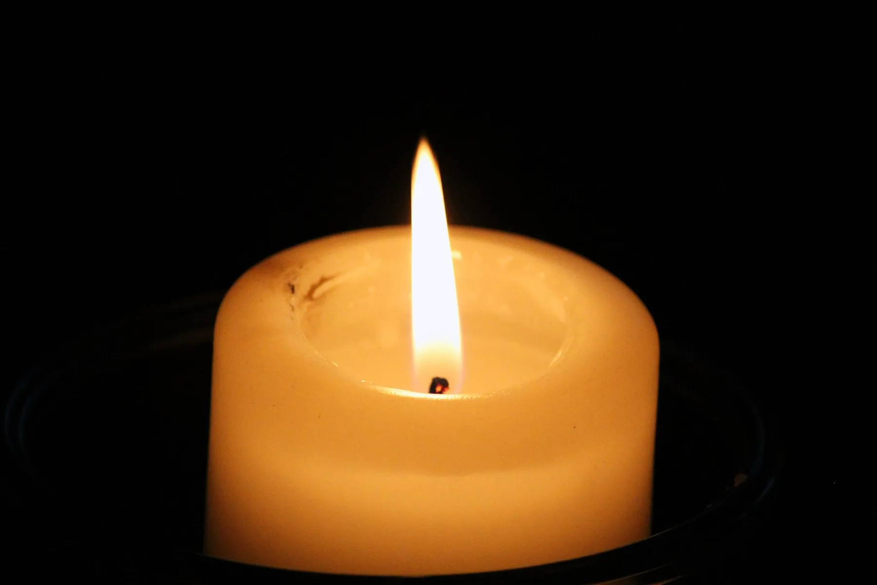 A single lit candle glowing in the dark